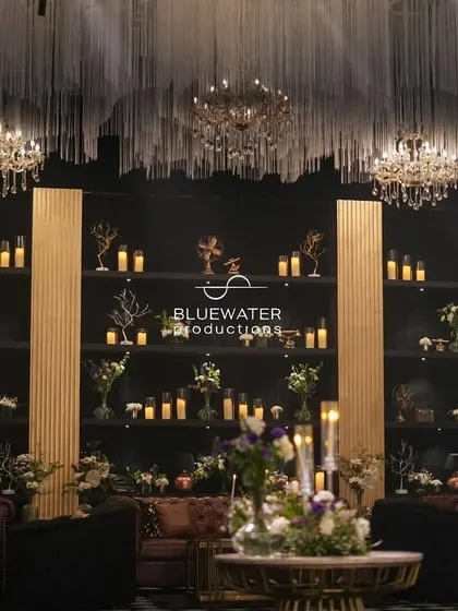 Behind the lounge seating, a massive shelving unit filled with candles and curiosities creates a stunning and atmospheric backdrop.