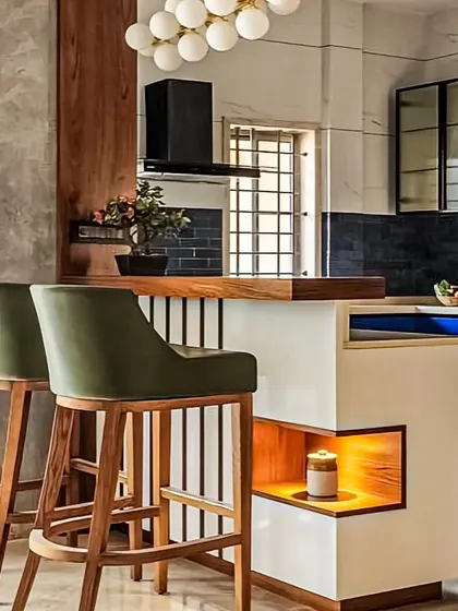 A close-up of a custom-designed breakfast bar. The combination of wood, white laminate, and slatted details, along with built-in niche lighting, adds a bespoke touch to the kitchen.