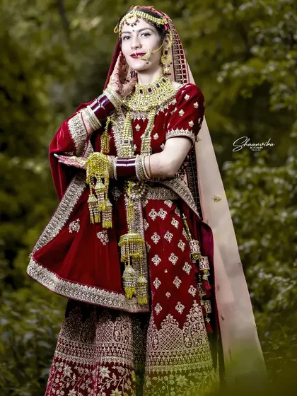 A full-length portrait of the bride in her stunning red velvet lehenga, showcasing the traditional Himachali jewelry and style.