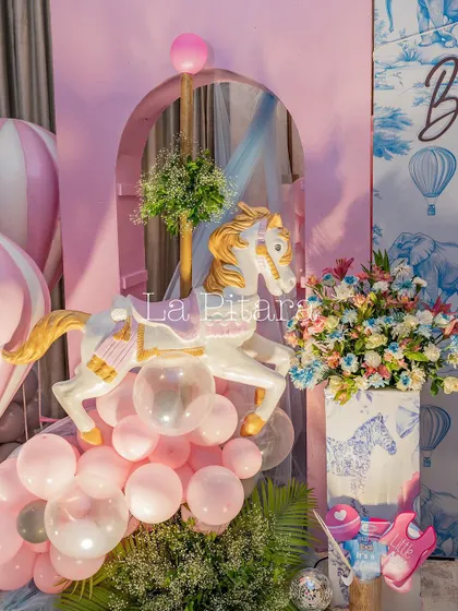 A beautiful decor element from the Baby Dior shower, featuring a carousel horse, pink balloons, and floral arrangements in a themed vase.