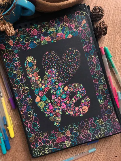 The "LOVE" artwork surrounded by the gel pens used to create it.