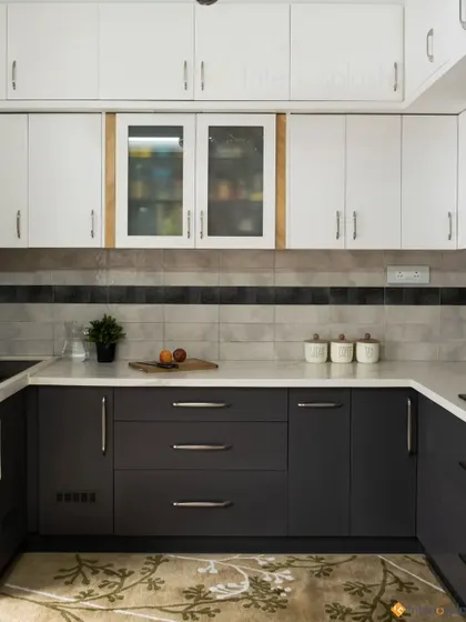 Another view of the two-tone kitchen, highlighting the practical layout and ample storage. The patterned rug adds a touch of color and personality.