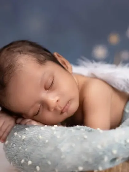 A tiny angel sleeping on a cloud. This newborn portrait features delicate angel wings and a dreamy, starry background, creating a heavenly and serene image.