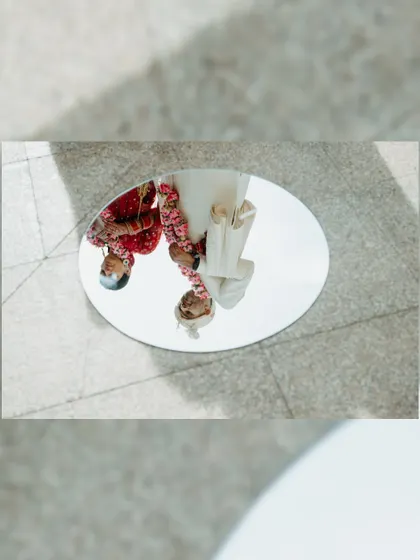 An artistic reflection of the couple in a mirror on the ground, a creative way to capture their portrait during the ceremony.