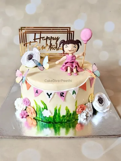 This red velvet cake for a little girl's birthday has a lovely garden theme. It features a hand-painted grass effect, sugar flowers, and a cute fondant figurine holding a balloon.