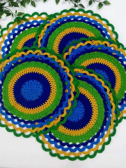 A set of six peacock placemats spread out, showing how they look as a complete dining set. The colors are so lively and eye-catching.