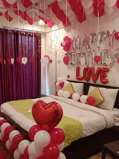 Another view of the red and white romantic room setup, showing balloon pillars with heart foil toppers.
