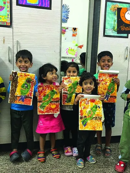 A whole group of proud artists with their textured parrot artworks. This project involved layering materials to create a 3D effect, which is a great sensory experience.