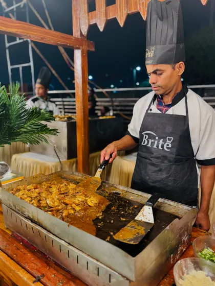 Another chef preparing a large batch of sizzling prawns at the teppanyaki station.
