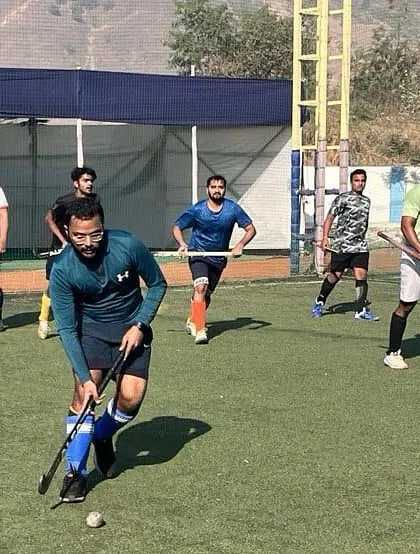 A player dribbles the ball up the field, looking for a teammate to pass to. Our training emphasizes field awareness and strategic play.