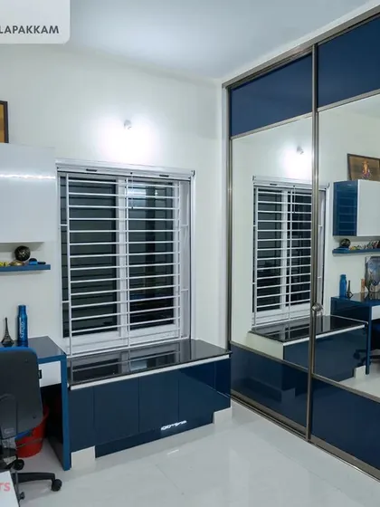 A functional and stylish kids' bedroom in the Sithalapakkam villa, with a blue and white color scheme, a built-in study desk, and a large mirrored sliding wardrobe.