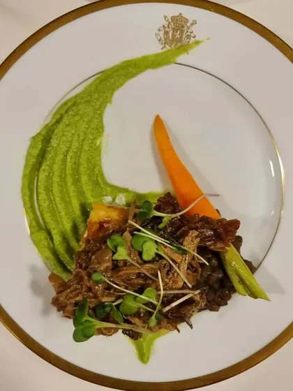 Pulled lamb with a pea puree and microgreens, served on elegant gold-rimmed china. For our sit-down dinners, we can arrange for premium crockery and glassware to elevate the experience.