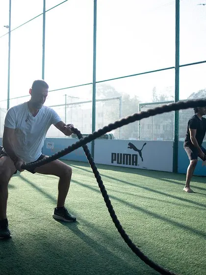 Two members using battle ropes with intense focus. This shows that our workouts incorporate modern functional tools alongside traditional ones for a comprehensive, high-intensity session.