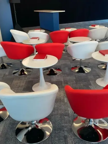 Modern and stylish seating for a corporate event or conference, featuring red and white bucket chairs with sleek tulip side tables.