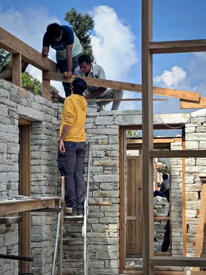 Our team members collaborate on the upper levels of a stone structure in Uttarakhand. Working at height on a sloping site requires immense skill, precision, and trust among the craftspeople.