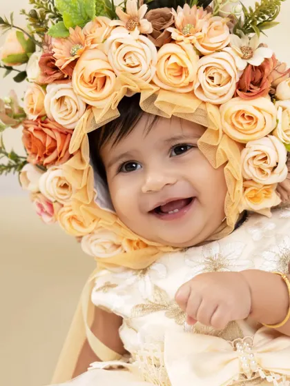A close-up on a radiant smile. This beautiful portrait highlights the intricate floral bonnet and, most importantly, the pure happiness on this little girl's face.