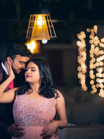 A tender moment during an engagement party, with the couple framed by warm lights and bokeh.