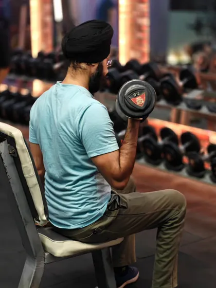 Focus and form are everything. A client performs a bicep curl with a dumbbell, concentrating on the muscle contraction to get the most out of every repetition.