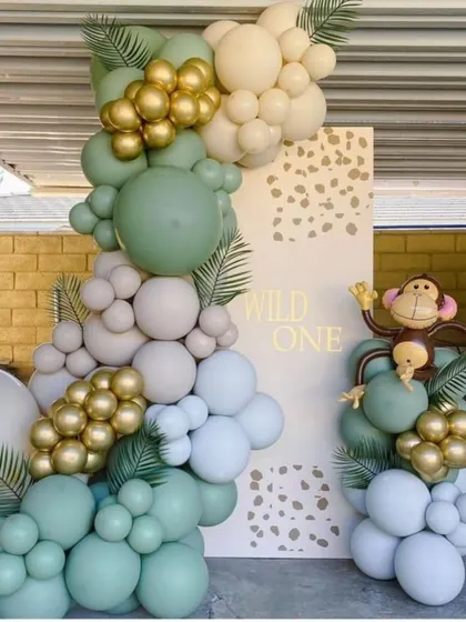 A stylish 'Wild One' jungle theme with a modern, minimalist backdrop and a beautiful balloon garland in sage green, white, and gold.