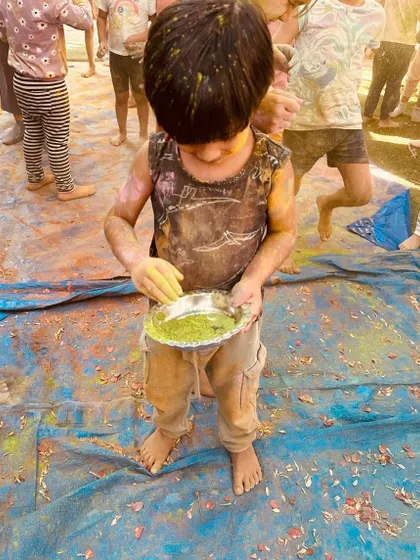 A young child fully immersed in the joy of Holi. We believe in allowing children the freedom to get messy and explore materials without inhibition.