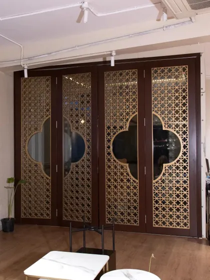 This set of four folding doors features intricate CNC-cut 'jali' work with a gold matte finish over a rich brown PU painted HDHMR base. It's a perfect solution for dividing a room while maintaining a sense of openness and artistry.