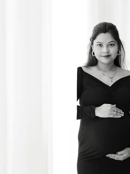 A simple and striking black and white portrait. The composition uses negative space effectively to draw attention to the mom-to-be.