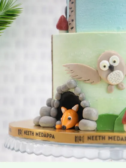 A peek at the lower tier of the jungle cake, where a fondant owl takes flight and a fox hides in its den.