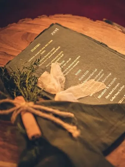 A custom menu printed on slate, tied with twine and a cinnamon stick, showing our rustic-chic details.