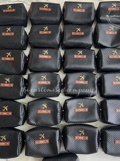 Make memories all over the world with our custom travel essentials. This image shows a large order of personalized black toiletry bags for a travel-themed event.
