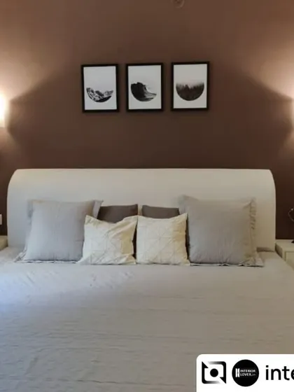 A simple and serene guest bedroom. The design uses a muted color palette with a deep brown accent wall and elegant wall sconces to create a warm and welcoming space for visitors.