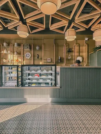 The bakery and cafe counter at the President Hotel features a geometric tiled floor and an intricate wooden lattice ceiling. These details add a layer of modern craftsmanship to the heritage-inspired space.