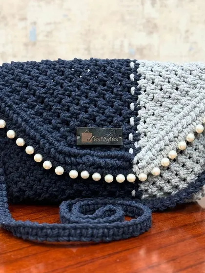 A beautiful two-tone sling bag in navy and grey, adorned with pearls for an elegant finish.