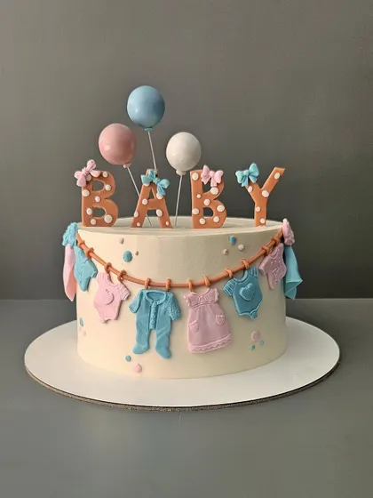 Lil feet on the way! A sweet baby shower cake with a clothesline of baby onesies. The pastel pink and blue colors make it a perfect choice for a gender-neutral celebration.