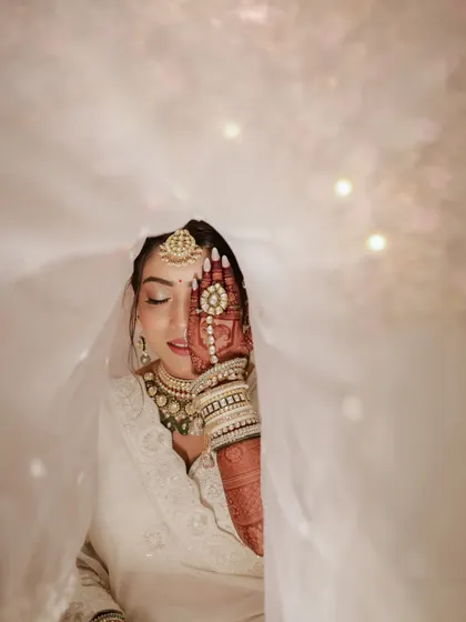 An artistic pose with the bride's henna-covered hand partially covering her face. A creative and beautiful bridal portrait.