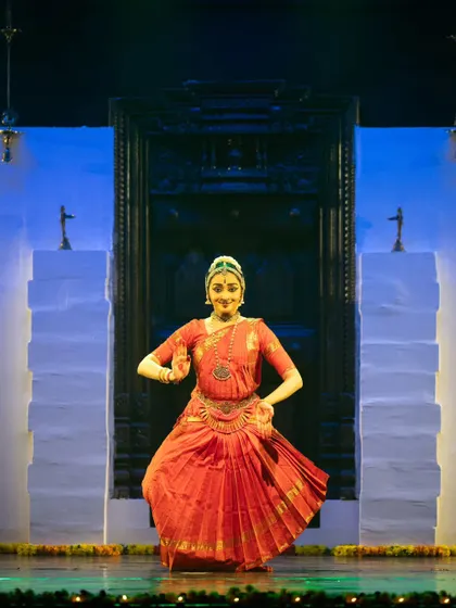 A full-length pose showing the traditional Bharatanatyam stance against the backdrop of a stage set designed to look like a temple.