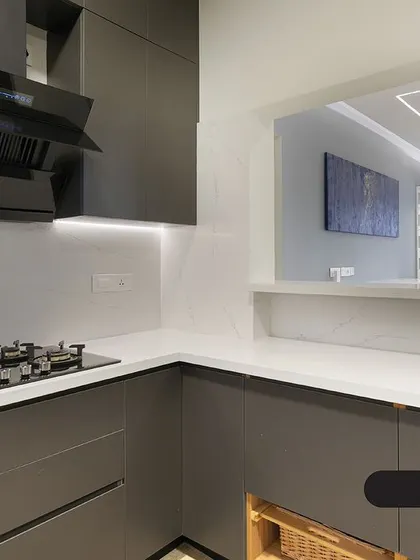 A matte grey kitchen that exudes modern sophistication. The dark cabinets are balanced by a white marble-effect backsplash and a pass-through window that connects to the living area.