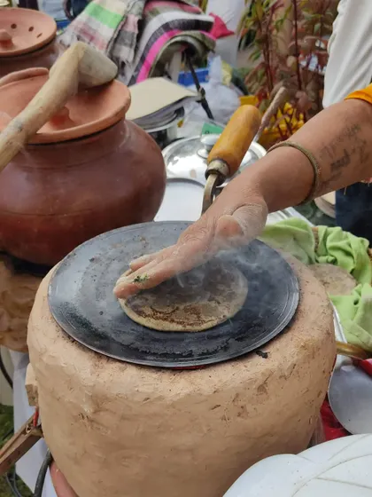 A woman making fresh roti on a traditional clay stove (*chulha*), a common sight at the market.