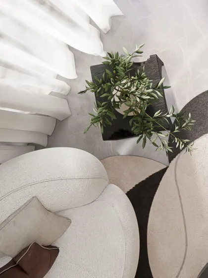 An overhead shot showing the soft, curved forms of the furniture and the layered, geometric rug, which add softness to the clean lines of the architecture.