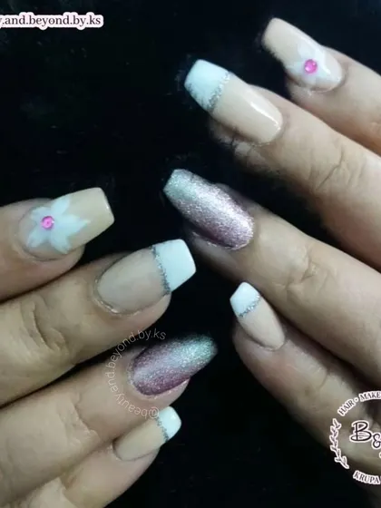 A close-up detail shot of the glitter ombre ring finger and the hand-painted flower on these custom French tip nails.