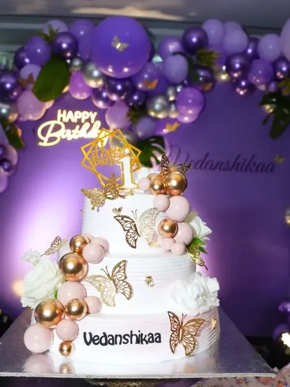 The cake is the centerpiece of any birthday. I coordinated with the baker for this stunning three-tier butterfly-themed cake, which perfectly matched the purple and gold balloon decor I set up for a first birthday.