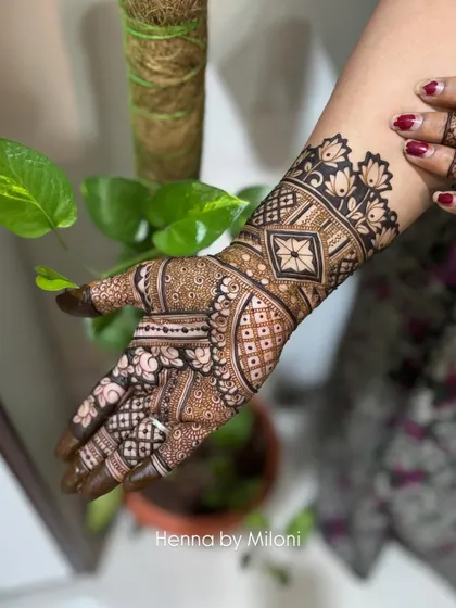 A detailed design on the back of the hand, featuring a lotus cuff and a mix of floral and geometric patterns.