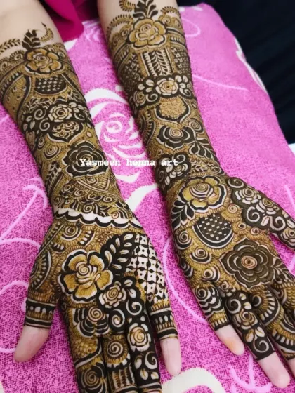 This bridal design combines bold floral work with delicate lattice patterns on the fingers, creating a beautiful contrast.