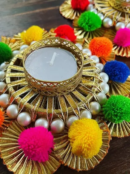 The combination of golden gota patti, colorful pompoms, and classic pearls gives these tea light holders a traditional yet playful look for your festive decor.