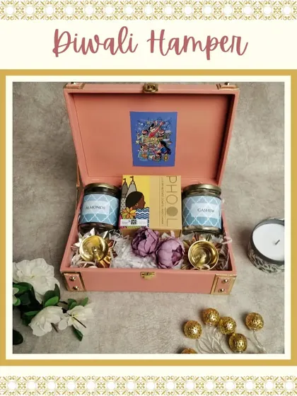 A beautiful pink trunk box hamper for Diwali. This set includes two jars of dry fruits, a box of Phool incense, and two brass diyas, offering a mix of traditional and modern items.