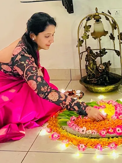 A client celebrating Diwali with a beautiful floral rangoli, wearing a custom printed blouse.