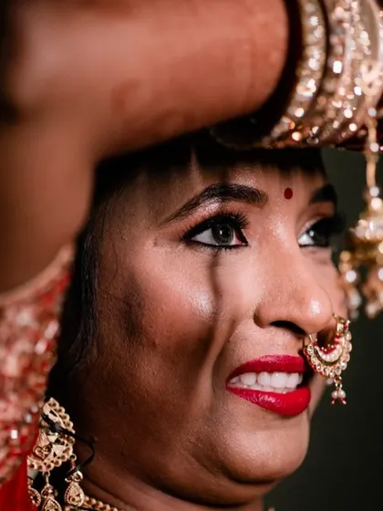 A candid moment of a North Indian bride during the ceremony, her expression full of emotion as she holds her hands up.