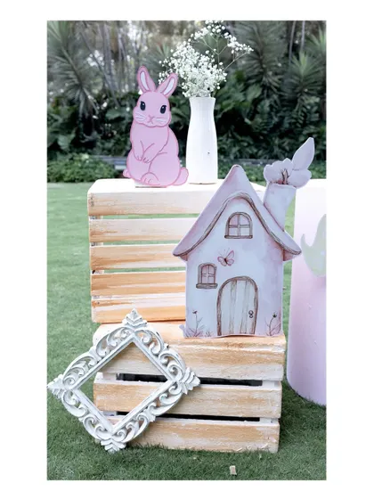 A charming decorative corner with rustic wooden crates, a pink bunny cutout, and a miniature fairy house, perfect for adding detail to a woodland or garden party.