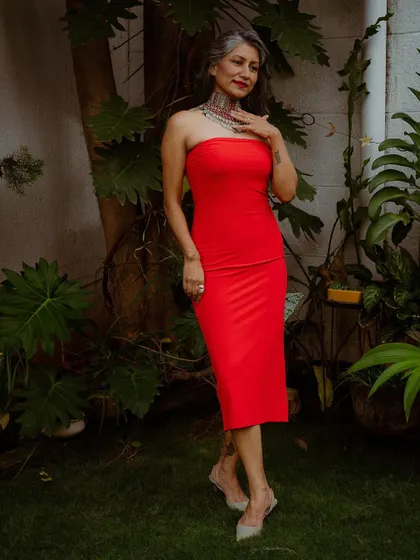 I believe in redefining beauty standards by embracing my silver hair. Here, I've paired a simple, bold red dress with a statement Afghani choker to create a powerful look.
