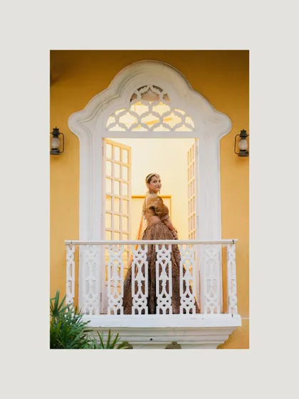 A beautiful bridal portrait of the bride standing on a balcony, framed by the classic architecture of the Goan venue.