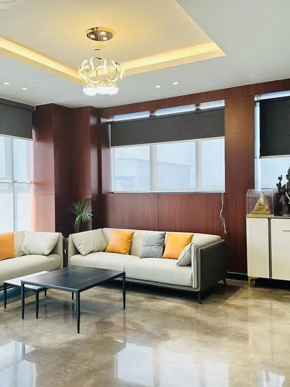 A complete view of the executive waiting lounge, showing the combination of comfortable seating, modern lighting, and functional elements like the credenza.